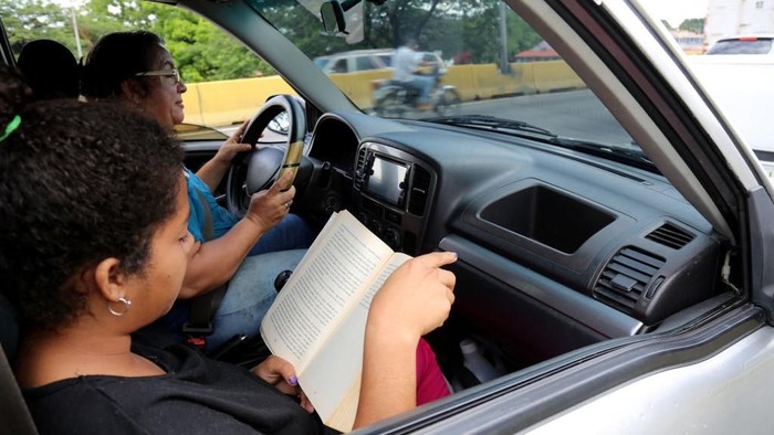 VALENCIA, VENEZUELA - MAY 24: A woman reads a book as she waits along with another to fill teir car tank suring a fuel shortage on May 24, 2019 in Valencia, Venezuela. Main reasons of the shortage are the sanctions imposed by the US government, the lack of additives and mismanagement which led to a drastic reduction in the refinery capacity. Experts expect shortages impact Caracas in the next days. (Photo by Edilzon Gamez/Getty Images)