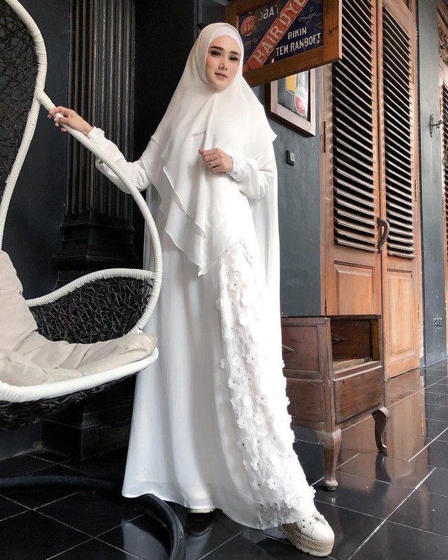 Anda yang menggunakan hijab syari bisa melirik gaya Mulan Jameela. Ia mengenakan gamis putih dengan aksen bunga 3D. Tentunya hijab pun dipilih yang senada. Saat memakai terusan panjang, Anda bisa menggunakan sepatu hak tinggi agar siluetnya lebih indah dilihat.  Foto: Instagram