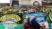 Pengendara sepeda motor melintas di depan karangan bunga duka cita untuk Ani Yudhoyono, Minggu (2/6/2019). 