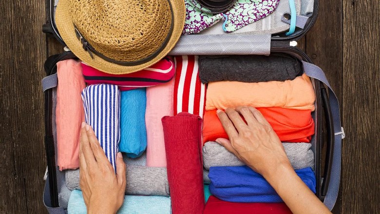 Woman hand preparing summer luggage