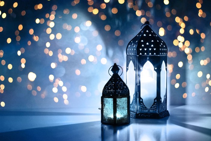 Ilustrasi Lebaran atau Idul Fitri Couple of glowing Moroccan ornamental lanterns on the table. Greeting card, invitation for Muslim holy month Ramadan Kareem, festive blue night background with glittering golden bokeh lights.