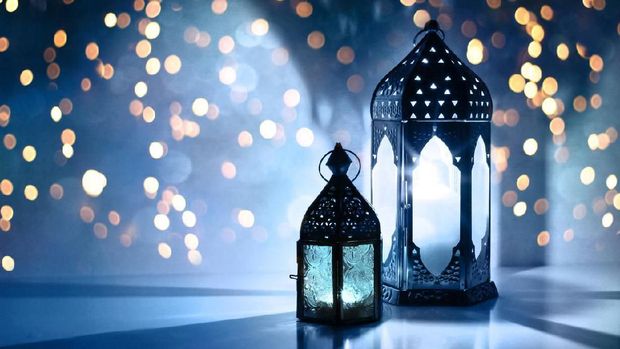 Couple of glowing Moroccan ornamental lanterns on the table. Greeting card, invitation for Muslim holy month Ramadan Kareem, festive blue night background with glittering golden bokeh lights.