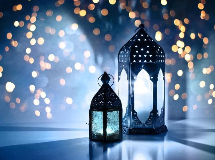 Ilustrasi Lebaran atau Idul Fitri Couple of glowing Moroccan ornamental lanterns on the table. Greeting card, invitation for Muslim holy month Ramadan Kareem, festive blue night background with glittering golden bokeh lights.
