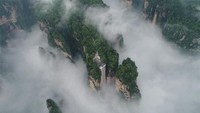Penampakannya yang diselimuti kabut membuat lift ini tampak seperti menembus awan di ketinggian 326 meter. Lift ini akan membawa kita pada puncak tebing dengan ketinggian 330 meter. Foto: Dok. Xinhuanet/Wu Yongbing