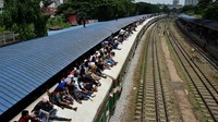 Orang-orang duduk di atas kereta yang terparkir di stasiun kereta api untuk pulang menjelang Idul Fitri. Salim Reza/Xinhuanet.