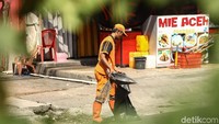 Pasukan Oranye menyusuri jalanan di kawasan Gambir untuk membersihkan sampah.