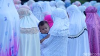 Seorang anak digendong orangtuanya saat Salat Idul Fitri di Gedung BI.