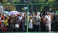 Warga menunggu dari luar pagar.