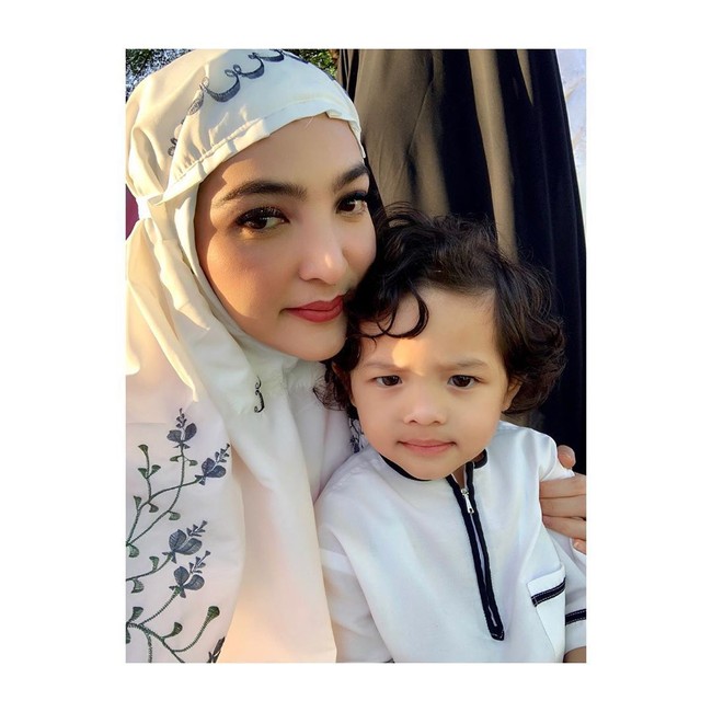 Penyanyi Ashanty tetap terlihat cantik saat Salat Idul Fitri meski mengaku kurang tidur. Ashanty memilih mukena putih dengan detail bordiran bunga. (Foto: Instagram)