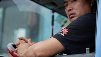 Sopir bus memakai kaos Huawei, tugasnya mengemudikan bus di sekeliling kantor pusat. Foto: Reuters