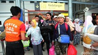 Para pemudik keluar stasiun dengan menenteng sejumlah tas.
