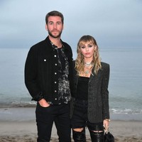 Liam Hemsworth dan Miley Cyrus menunjukkan kemesraan dengan gaya busana kompaknya yang serba hitam dari Saint Laurent. (Foto: Neilson Barnard/Getty Images)