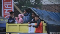 Warga terlihat sangat semringah saat menumpang truk terbuka.