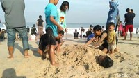Sejumlah wisatawan nampak bermain pasir di Pantai Santolo Garut, Jawa Barat, Minggu (9/6/2019).