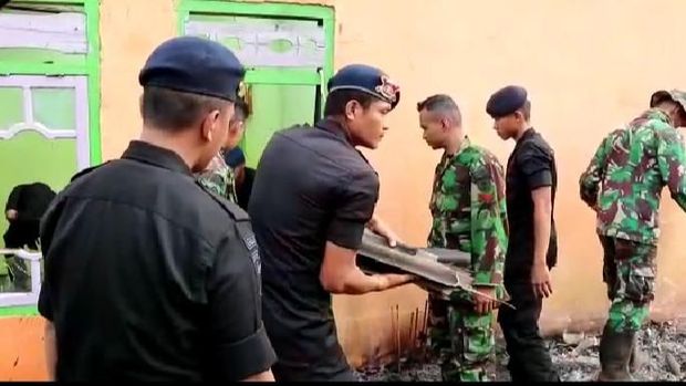 Personel TNI dan Polri saling bantu mengangkat puing.