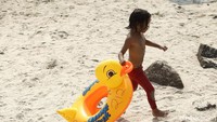 Seorang anak kecil membawa ban untuk berenang di Pantai Ancol.