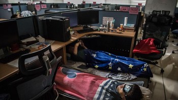 Dua pegawai Huawei tampak tertidur dengan lelap di tengah ruang kerja yang sepi karena banyak yang keluar untuk makan siang atau aktivitas lain. Foto: Getty Images