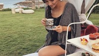 Happy weekend tulis Angela pada unggahan fotonya ini. Terlihat angela tengah menikmati segelas teh dan aneka kudapan di pinggir pantai.  Foto: instagram @angelagilsha
