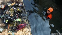 Seorang petugas Prasarana dan Sarana Umum (PPSU) atau Pasukan Oranye mengumpulkan sampah yang hanyut di selokan kawasan Muara Angke, Jakarta, Selasa (11/2/2019).