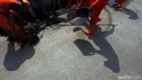 Setiap petugas tampak dibekali sapu untuk membersihkan sampah yang berceceran.