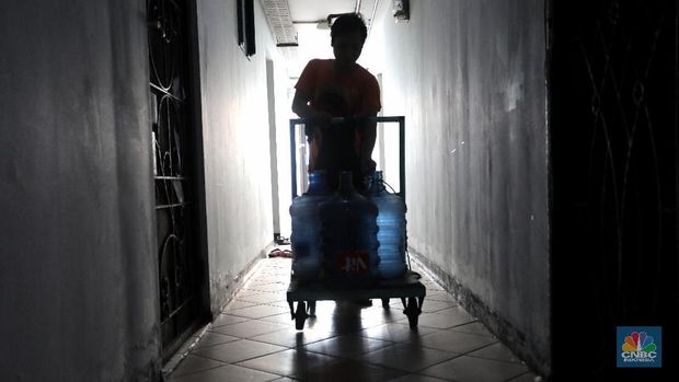 Pedagang air galon membawa galon yang sudah diisi penuh untuk dijual ke warga apartemen di Kawasan Pluit, Jakarta, Rabu (12/6). Banyak penghuni apartemen di kawasan tersebut menggunakan air galon isi ulang untuk mandi. Mumun seorang pembantu rumah tangga mengatakan majiakannya bisa menkonsumsi air galon sehari 4-5 galon untuk mandi dan cuci piring. Harga galon isi ulang ia beli seharga Rp 3500 yang berasal dari air pam, Rp 7000 untuk galon isi ulang untuk galon asli Rp.20.000. Banyak penghuni apartmen menggunakan air galon karena air yang mereka tempati kadang bau dan kotor. (CNBC Indonesia/Muhammad Sabki)