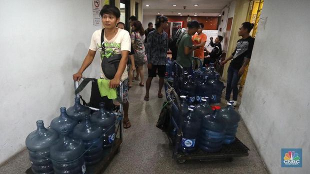 Pedagang air galon membawa galon yang sudah diisi penuh untuk dijual ke warga apartemen di Kawasan Pluit, Jakarta, Rabu (12/6). Banyak penghuni apartemen di kawasan tersebut menggunakan air galon isi ulang untuk mandi. Mumun seorang pembantu rumah tangga mengatakan majiakannya bisa menkonsumsi air galon sehari 4-5 galon untuk mandi dan cuci piring. Harga galon isi ulang ia beli seharga Rp 3500 yang berasal dari air pam, Rp 7000 untuk galon isi ulang untuk galon asli Rp.20.000. Banyak penghuni apartmen menggunakan air galon karena air yang mereka tempati kadang bau dan kotor. (CNBC Indonesia/Muhammad Sabki)