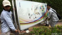 Petugas menggotong neon box yang baru dicopot.