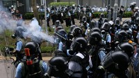 Jajaran polisi antihuru-hara yang memakai masker dan helm, tampak siaga mengawal aksi protes ini. Namun mereka dilaporkan kalah jumlah dengan para demonstran. Pada Rabu (12/6) pagi menuju siang, jumlah demonstran semakin bertambah. Di luar gedung Dewan Legislatif, polisi menembakkan meriam air dan mengerahkan semprotan merica untuk mengendalikan para demonstran. REUTERS/Athit Perawongmetha.