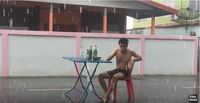 Hujan Deras, Pria Ini Lanjut Makan Mie dan Minum di Tengah Jalan