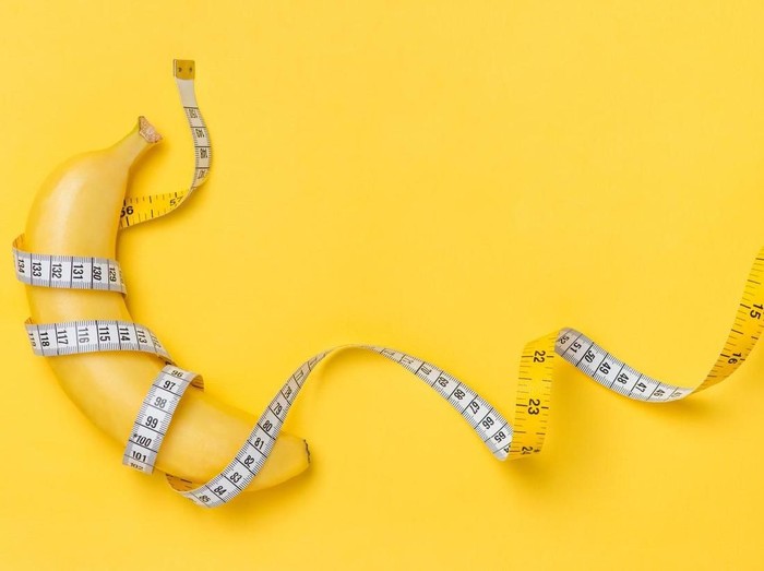 871553024 Diet, fitness and health concept presented by yellow banana wrapped in measure tape isolated on yellow paper background