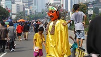 Pengamen ondel-ondel mengais rezeki dengan menghibur pengunjung car free day.