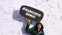Warga membawa poster bertuliskan pesan damai dalam deklarasi menolak kerusuhan.