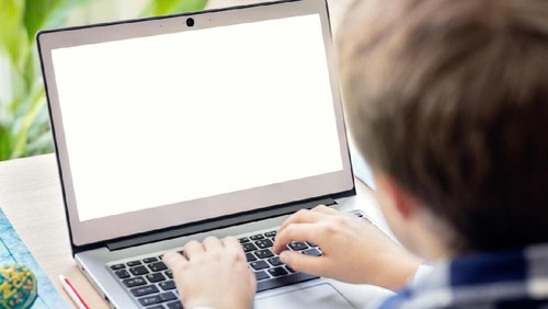 Boy on the internet with laptop computer doing homework with blank screen