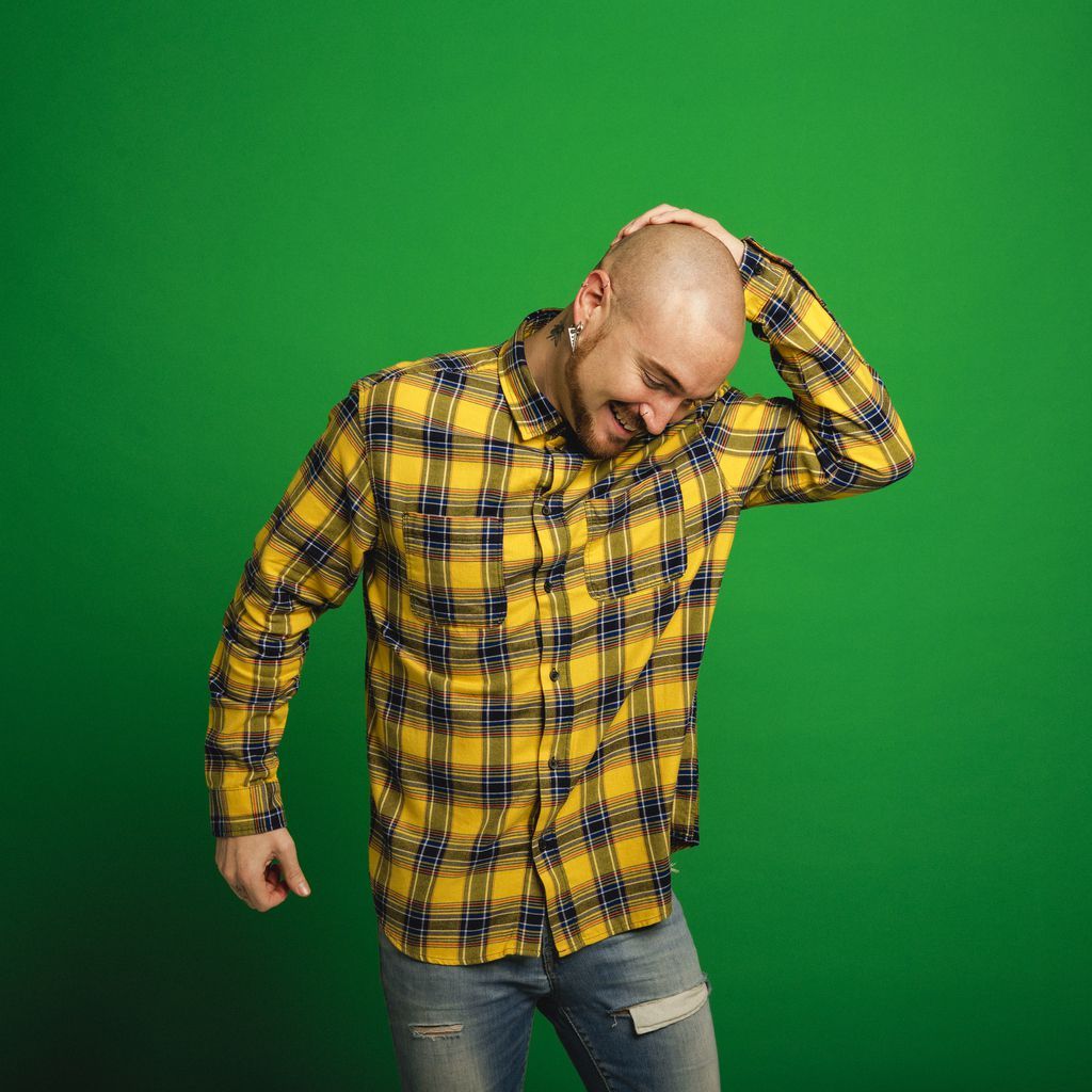 Mid adult hipster man dancing infront of a green studio background.