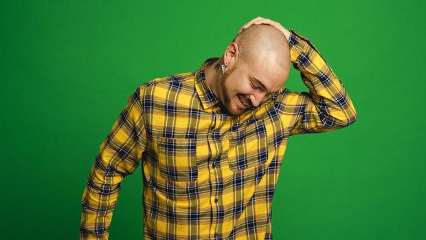 Mid adult hipster man dancing infront of a green studio background.