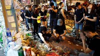 Berbagai benda turut diletakkan, mulai dari karangan bunga, dupa, lilin hingga sebotol wiski dan topi putih bertuliskan pahlawan diletakkan di lokasi jatuhnya demonstran tersebut. Tyrone Siu/Reuters.