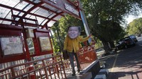Warga menggunakan topeng wajah Setya Novanto nampak menunggu bus di Halte Sriwedari dalam aksi bertajuk Setya Novanto Plesiran di Solo.