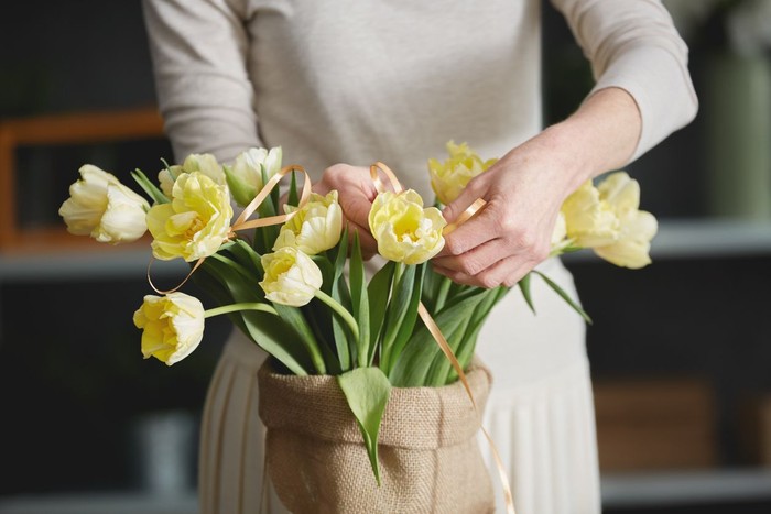 Woman arranging a bunch of yellow flowers in flower shop