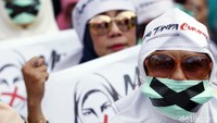 Seorang peserta aksi mengenakan masker dengan simbol x saat ikut serta dalam aksi damai di kawasan Patung Kuda, Jakarta.