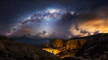 Setiap tahun sekitar bulan September dan Oktober, fenomena alam Bima Sakti berada pada posisi terbaiknya. Inti galaksi berada tepat di tengah-tengah langit. Fotografer berdiri di tebing dekat laut dan dengan obornya ia menyalakan jembatan alami, yang tampak seperti lubang raksasa.  (Foto: Astronomy Photographer 2019)