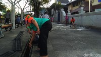 Warga dan para pedagang bersama-sama membersihkan trotoar.