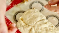 Agar cinnamon roll tidak pipih saat dipotong, gunakanlah benang. Ikat benang melingkar dan tarik hingga adonan terpotong. Foto: Istimewa