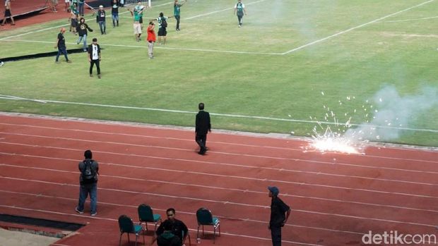 Massa suporter juga melempar petasan ke dalam stadion