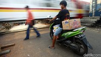 Pemotor menunggu kereta api melintas di kawasan Pintu Air Karet, Jakarta, Rabu (19/6/2019). 