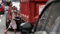 Seorang pengamen nampak menggendong anak saat mencari uang di Jalan Cideng Barat, Jakarta, Kamis (20/6/2019).