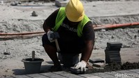 Seorang pekerja nampak sibuk mengerjakan proyek revitalisasi trotoar yang berada di Halte Tosari, Jakarta.