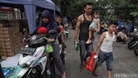 Warga membawa sembako hasil berbelanja di pasar murah yang digelar di RPTRA Budi Mulya, Penjaringan, Jakarta Utara.
