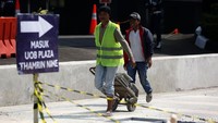 Sejum;ah petugas membawa bahan bangunan untuk mengerjakan proyek revitalisasi trotoar di Halte Tosari, Jakarta.