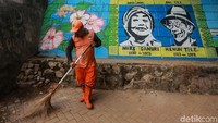 Seorang petugas PPSU nampak membersihkan area sekitar mural yang berada di kolong tol di Pesanggrahan, Jakarta.