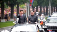 Kim Jong Un dan Xi Jinping melambaikan tangan kepada masyarakat saat konvoi menuju gedung pertemuan. North Koreas Korean Central News Agency (KCNA) via Reuters.